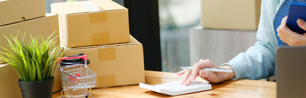 shipping-cost-calculation-parcels-on-the-desk-woman-uses-calculator-WerbeCenter-Berlin