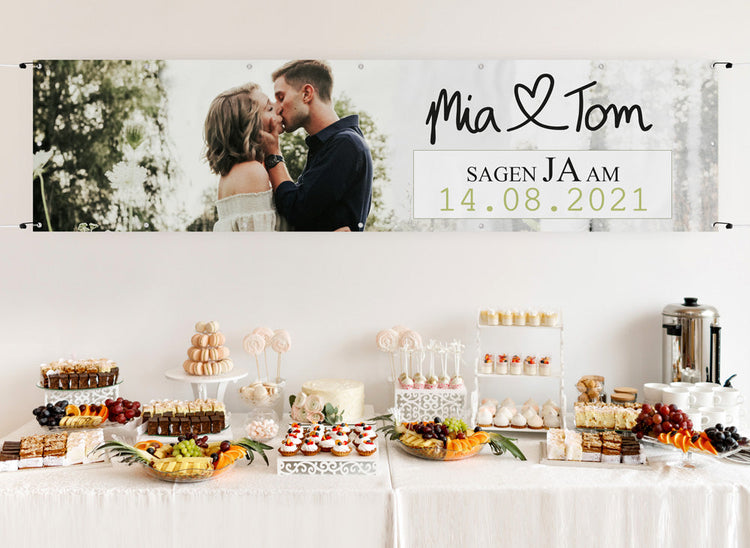 Personalisierbares Hochzeitsbanner mit Foto des Paares und individuellem Hochzeitsdatum, dekorativ über einem Buffet befestigt.