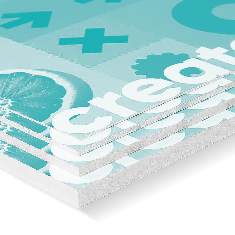 Nahaufnahme von mehreren übereinander gestapelten, weißen Platten, die mit einer türkisfarbenen Grafik bedruckt sind, die Zitrusfrüchte und das Wort "create" in großen, weißen Buchstaben zeigt. Die Kanten der Platten sind sauber und ordentlich, was dem Bild einen modernen und professionellen Eindruck verleiht.