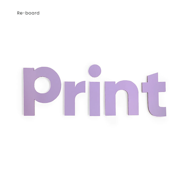 Das Bild zeigt Fräsbuchstaben aus Reboard Pappe in lila. Die Buchstaben bilden das Wort "Print", wobei die Seitenansicht der Wellpappe an den Rändern der Buchstaben sichtbar ist.