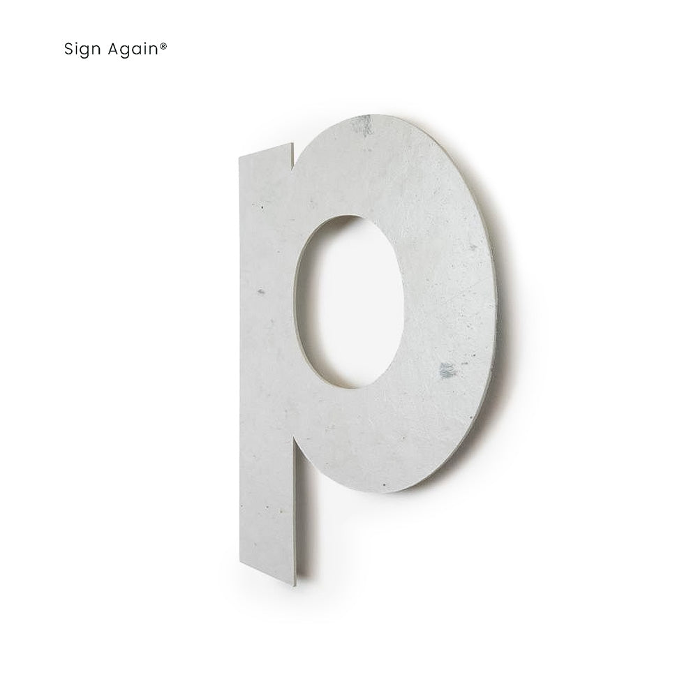 Weißes, dreidimensionales 'p' aus festem Material, das an einer Wand befestigt ist. Das Design ist minimalistisch und modern.