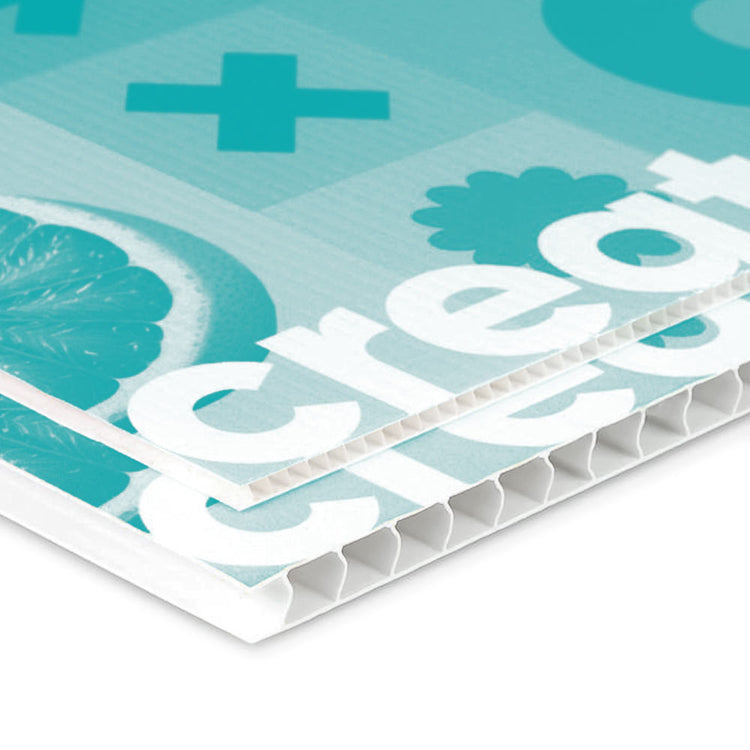Das Bild zeigt eine detaillierte Aufnahme einer bedruckten Kunststoffplatte mit einem grafischen Design. Die Platte ist in hellen Blautönen gehalten und enthält Symbole wie ein Pluszeichen sowie ein Stück Zitrusfrucht. Der Schriftzug „create“ ist gut sichtbar. Die Struktur der Platte ist in einem Wabenmuster erkennbar, was auf die Materialdichte und Festigkeit hinweist.