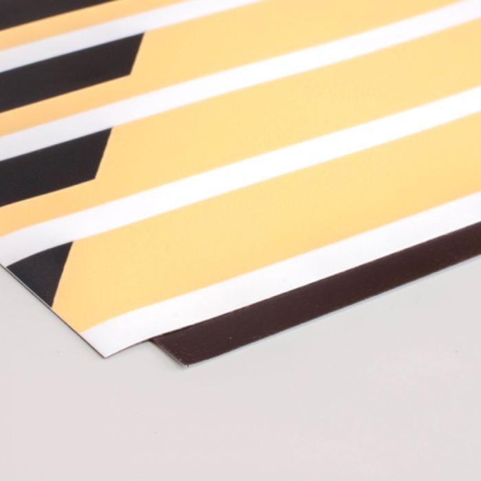 Das Bild zeigt einen Ausschnitt eines bedruckten Materials, das gelbe und schwarze Streifen mit weißen Trennlinien aufweist. Es könnte sich um eine Art Banner oder Plakat handeln, das eine klare geometrische Gestaltung aufweist. Der Rand des Materials ist gut sichtbar, und es scheint, dass es an den Rändern sauber geschnitten ist. Solche Designs könnten häufig in der Werbung oder in einer kreativen Präsentation verwendet werden.