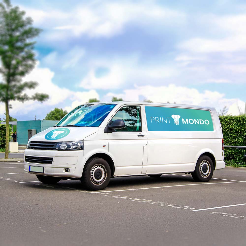 Das Bild zeigt ein weißes Lieferfahrzeug, das auf einem Parkplatz steht. Auf der Seite des Fahrzeugs ist ein auffälliger Aufkleber mit dem Logo von "PRINT MONDO" zu sehen, das ein blauer Schriftzug zusammen mit einem Elefanten-Symbol umfasst. Der Hintergrund des Bildes zeigt den Parkplatz und einen klaren, sonnigen Himmel mit Bäumen im Hintergrund.
