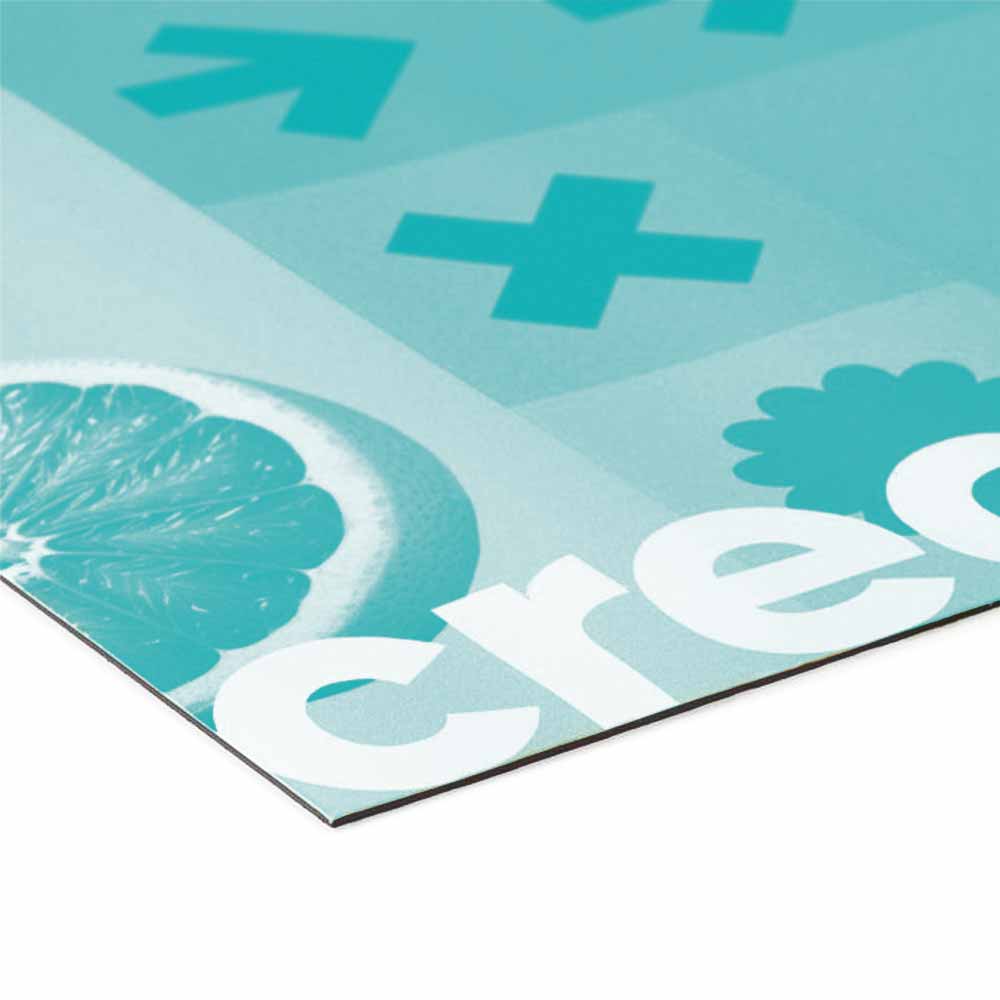 Das Bild zeigt eine Detailansicht eines bedruckten Materials. Die Ecke des Drucks zeigt eine farbige Grafik mit einer halbierten Grapefruit und den Worten "crec" in weißer, fetter Schrift, begleitet von weiteren grafischen Elementen wie Pluszeichen und einer grünen Blume. Die Farben sind in einem hellen Blau und Türkis gehalten, während der Rand des Materials deutlich sichtbar ist.
