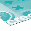 Das Bild zeigt eine Detailansicht eines bedruckten Materials. Die Ecke des Drucks zeigt eine farbige Grafik mit einer halbierten Grapefruit und den Worten "crec" in weißer, fetter Schrift, begleitet von weiteren grafischen Elementen wie Pluszeichen und einer grünen Blume. Die Farben sind in einem hellen Blau und Türkis gehalten, während der Rand des Materials deutlich sichtbar ist.