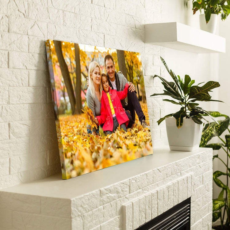 Personalisierte Leinwand mit einem herbstlichen Familienfoto, dekorativ auf einem Kaminsims platziert, umgeben von Pflanzen und weißen Regalböden.