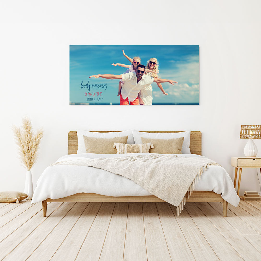 Große personalisierte Leinwand mit einem fröhlichen Familienfoto und der Aufschrift „Lovely Memories – Sommer 2023 – Cannon Beach“, stilvoll über einem Bett im modernen Schlafzimmer dekoriert.