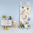 Ein personalisiertes Roll-Up Banner für einen ersten Geburtstag. Es zeigt mehrere Fotos eines Babys mit bunten, fröhlichen Elementen wie Luftballons und einem Zelt. Der Text „Noahs 1. Geburtstag“ sowie „Happy Birthday!“ sind auf dem Banner abgebildet. Das Banner steht in einem Kinderzimmer neben einem Holzspielzeug, einer blumigen Vase und einem kleinen Stuhl, was eine gemütliche und kinderfreundliche Atmosphäre schafft.