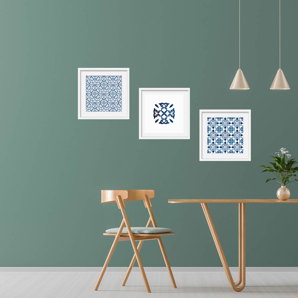 Set aus drei Wandbildern mit blauen und weißen Fliesenmustern an einer stilvollen grünen Wand. Perfekte Dekoration für ein modernes und skandinavisches Wohnambiente