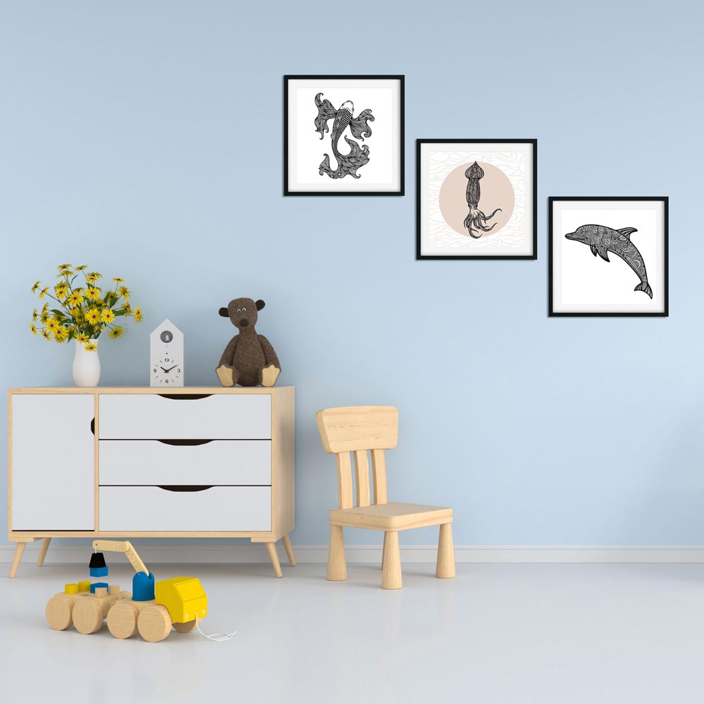 Drei Illustrationen von einem Koi-Fisch, Tintenfisch und Delfin in schwarz-weißer Farbgebung, eingerahmt und an einer Wand im Kinderzimmer angebracht, umgeben von Spielzeug und einer Kinderstuhleinrichtung.