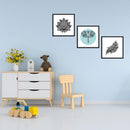 Drei dekorative Bilderrahmen mit handgezeichneten Designs: Ein Lotusblütenmuster, ein Elefant im Kreis mit kunstvollen Details und eine Feder mit zarten Mustern. Alle Bilder sind in schwarzen Rahmen präsentiert und bilden eine harmonische Wanddekoration. Als Dekoidee hängen die Poster an einer hellblauen Wand in einem Spielzimmer.