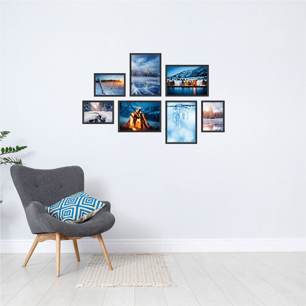 Poster-Collage mit winterlichen Landschaften und verschneiten Orten – stimmungsvolle Wanddeko im Winter-Design. Das sind die Rückansichten von dem Winter-Set, als Dekoidee in schwarzen Rahmen an einer weissen Wand neben einem grauen Sessel.