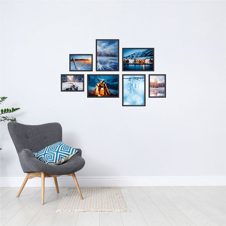 Poster-Collage mit winterlichen Landschaften und verschneiten Orten – stimmungsvolle Wanddeko im Winter-Design. Das sind die Rückansichten von dem Winter-Set, als Dekoidee in schwarzen Rahmen an einer weissen Wand neben einem grauen Sessel.