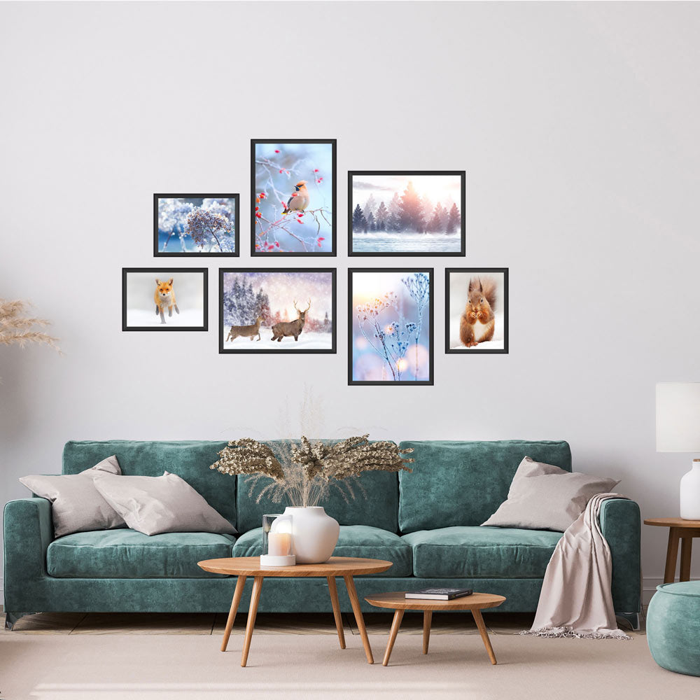 Poster-Collage mit winterlichen Naturmotiven: Vögel, Rehe, Fuchs, Eichhörnchen und verschneite Landschaften – stimmungsvolle Wanddeko im Winter-Design. Das sind die Vorderansichten von dem Winter-Set, als Dekoidee in schwarzen Rahmen an einer weissen Wand über einer grünen Couch.