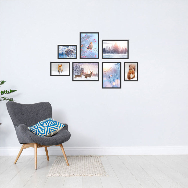 Poster-Collage mit winterlichen Naturmotiven: Vögel, Rehe, Fuchs, Eichhörnchen und verschneite Landschaften – stimmungsvolle Wanddeko im Winter-Design. Das sind die Vorderansichten von dem Winter-Set, als Dekoidee in schwarzen Rahmen an einer weissen Wand neben einem grauen Sessel.