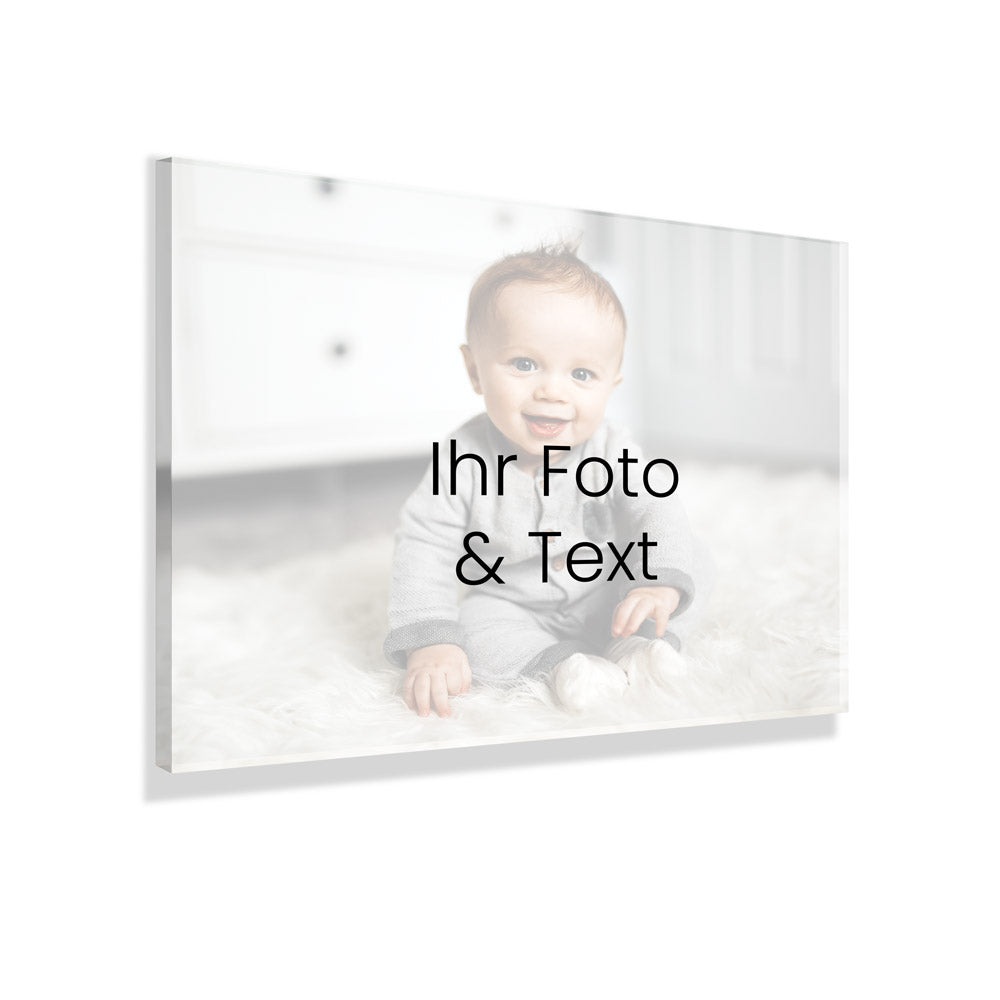 Individueller Fotodruck auf Acrylglas mit eigenem Text, Beispiel mit Babyfoto auf weichem Teppich. Der Hintergrund ist weiss.
