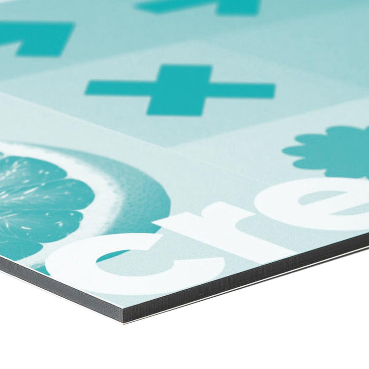 Material Detailbild einer Ecke von einem Alu-Dibond Schild mit einem türkisen Beispieldruck. Die Platte hat einen schwarzen Kern der hier gut gezeigt wird. Der Hintergrund ist weiss.