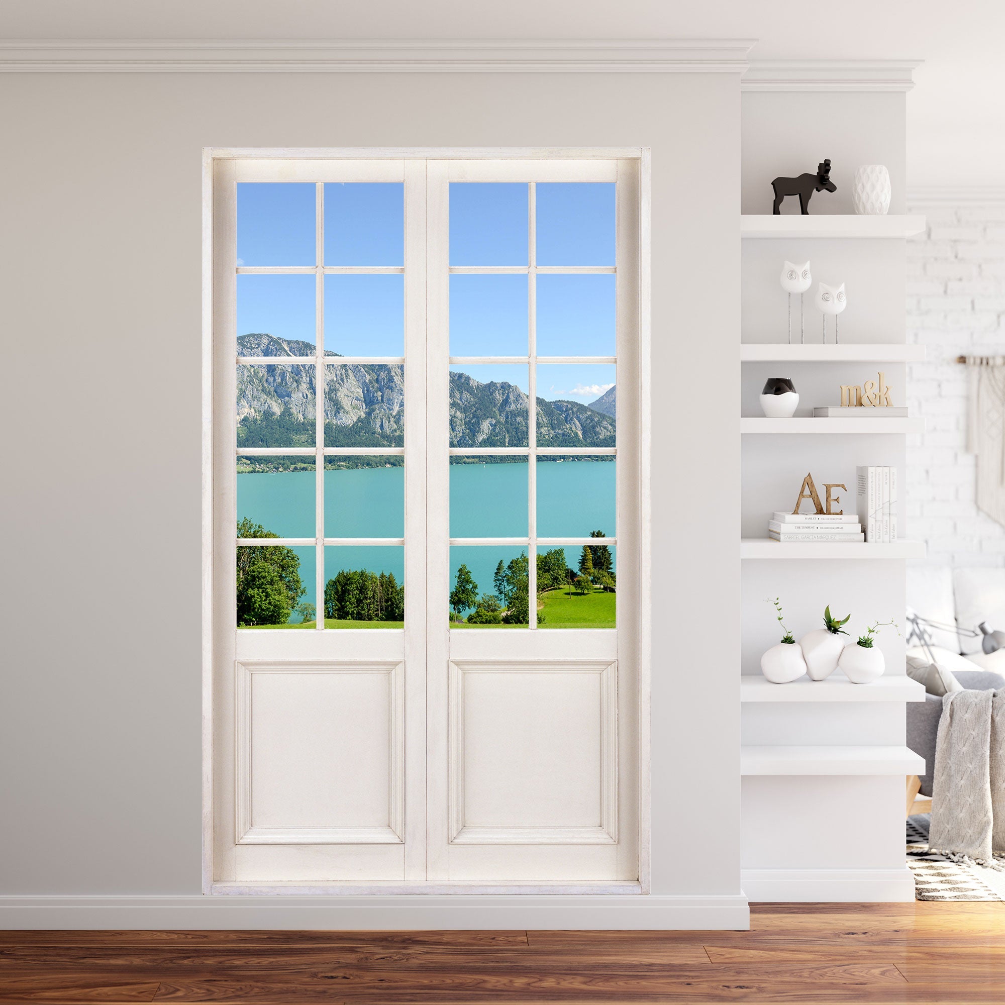 Modernes Wohnzimmer mit Bücherregal, mit Innendekoration Wandtattoo-Terrassentür 120x200cm Größe und Ausblick in die wunderbare Natur auf einen türkisen See vor den Alpen.