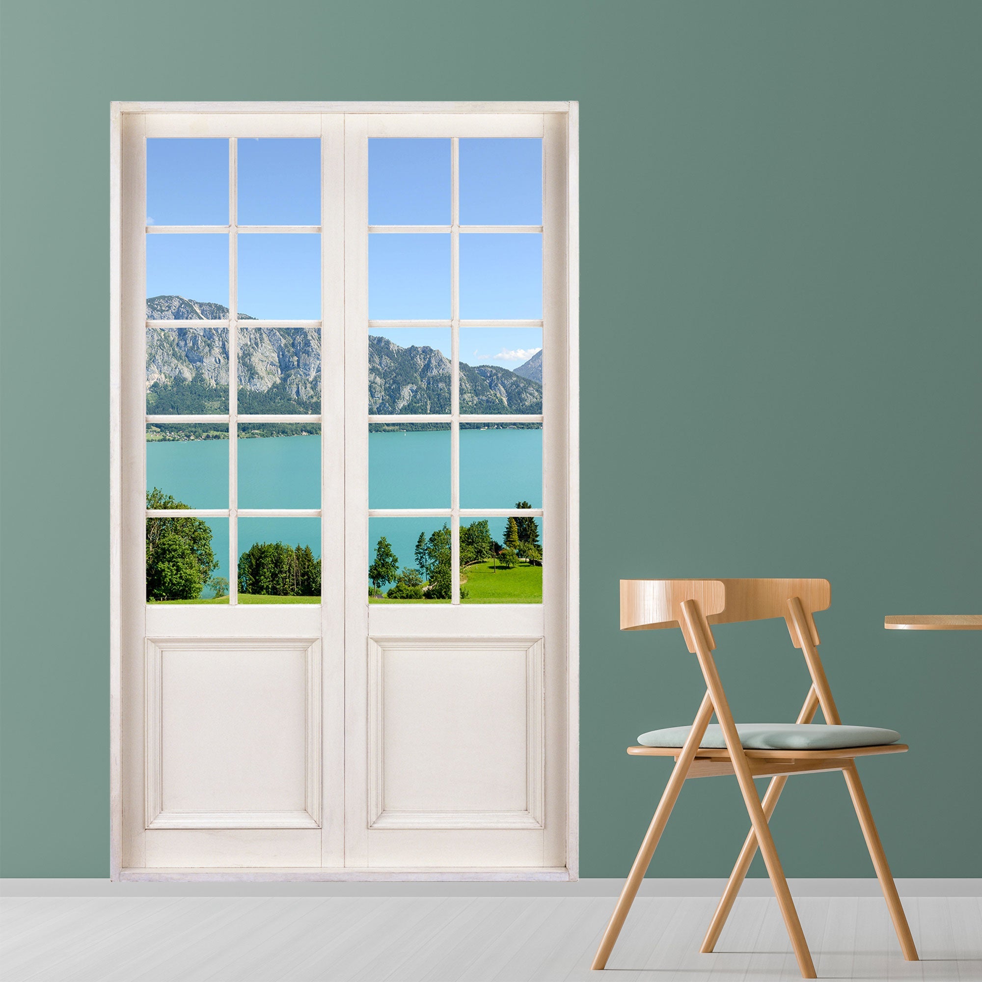 Moderner Essbereich mit Blickfang für Ihre Wohndekoration. Flügeltür mit optischer Täuschung und Ausblick auf einen wunderschönen See und Berge. Der Wandaufkleber ist als Idee an einer grünen Wand in einem Essbereich verklebt.