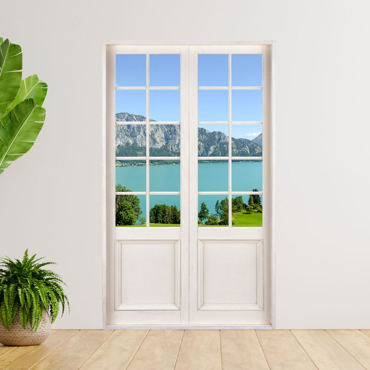 Selbstklebende Tür ins Grüne als Wandtapete mit traumhaften Blick auf   den Attersee in Österreich. Verklebt an einer weissen Wand neben großen Zimmerpflanzen.
