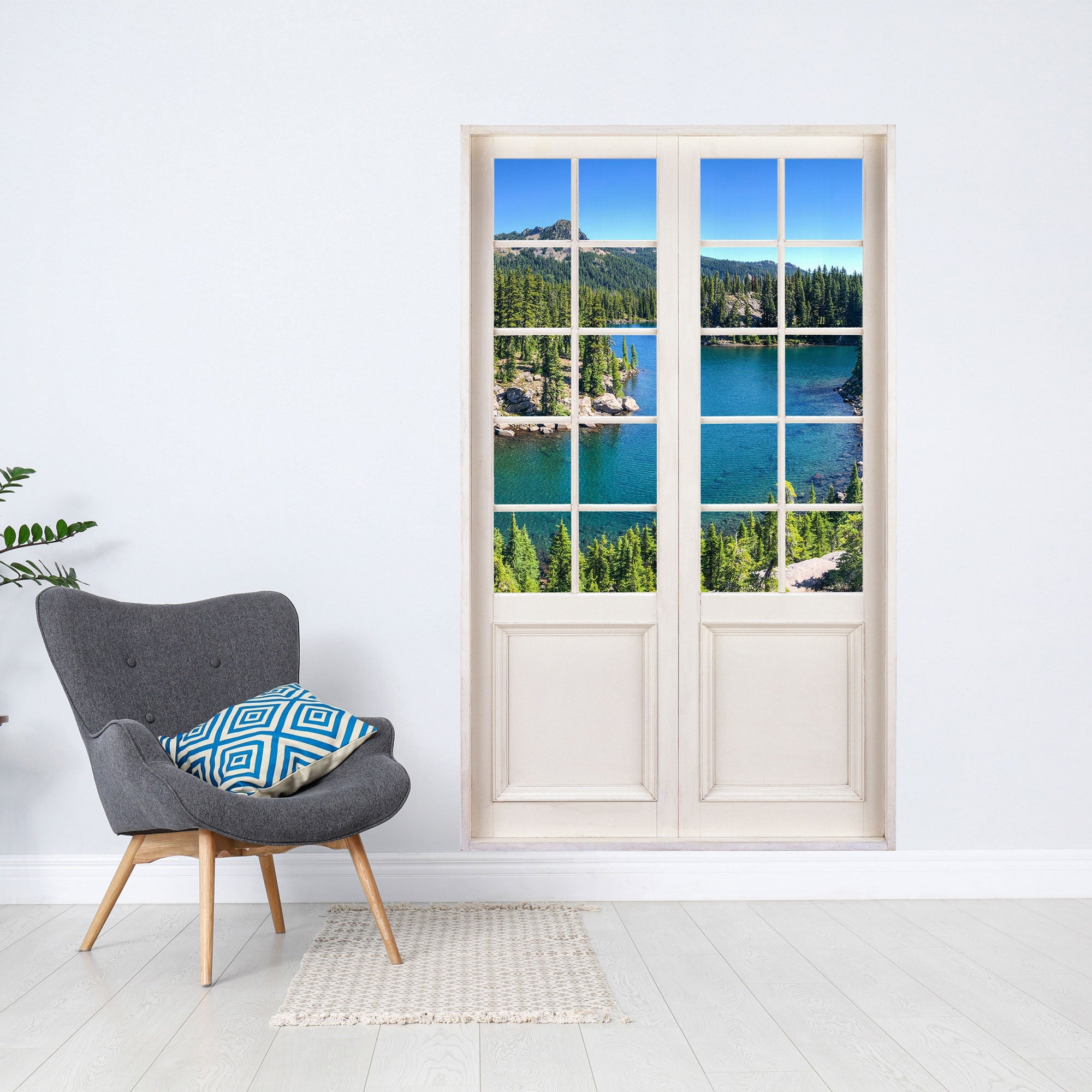 Wandtattoo bedruckt mit dem Bild einer weissen Sprossen-Terrassentür und Blick auf einen Bergsee mit Bergen und Wald. Als Größenvorstellung neben einem Sessel an der Wand verklebt.