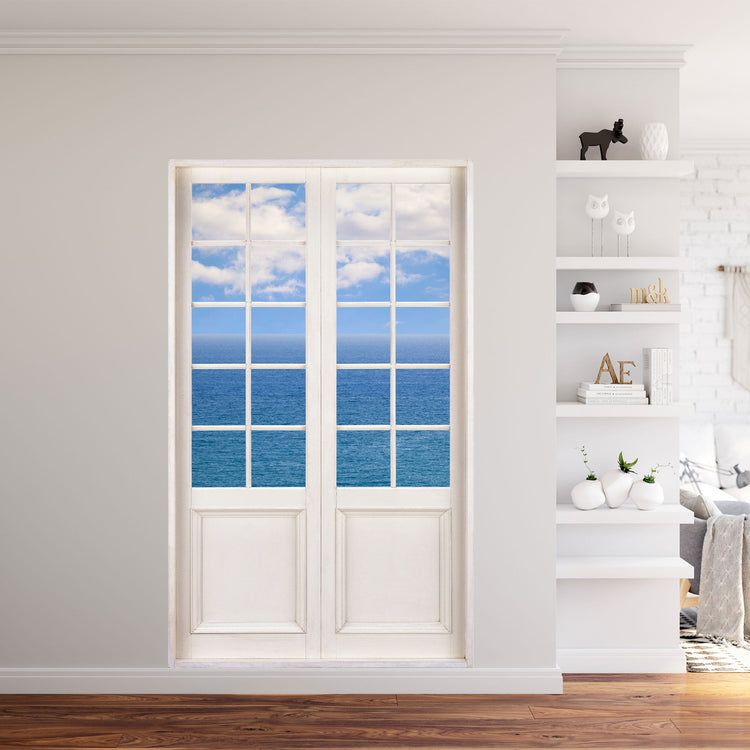 Gedrucktes Aufkleber-Wandbild für Tapete und Möbel, mit toller Aussicht auf das weite Meer mit Wolken. In einem Wohnzimmer neben einem Bücherregal.