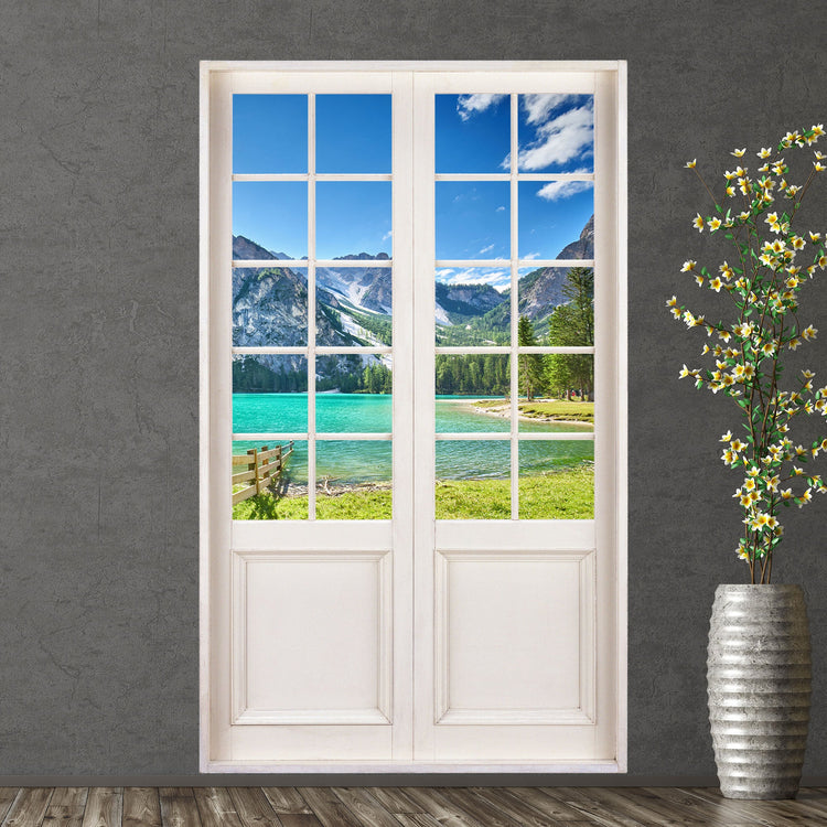 Dekorative Wohnraumgestaltung mit selbstklebendem Wandaufkleber in der Optik einer Terrassentür. Hier mit dem Foto von einem grünen Bergsee bei Sonnenschein, verklebt an einer grauen Wand neben einer Bodenvase.