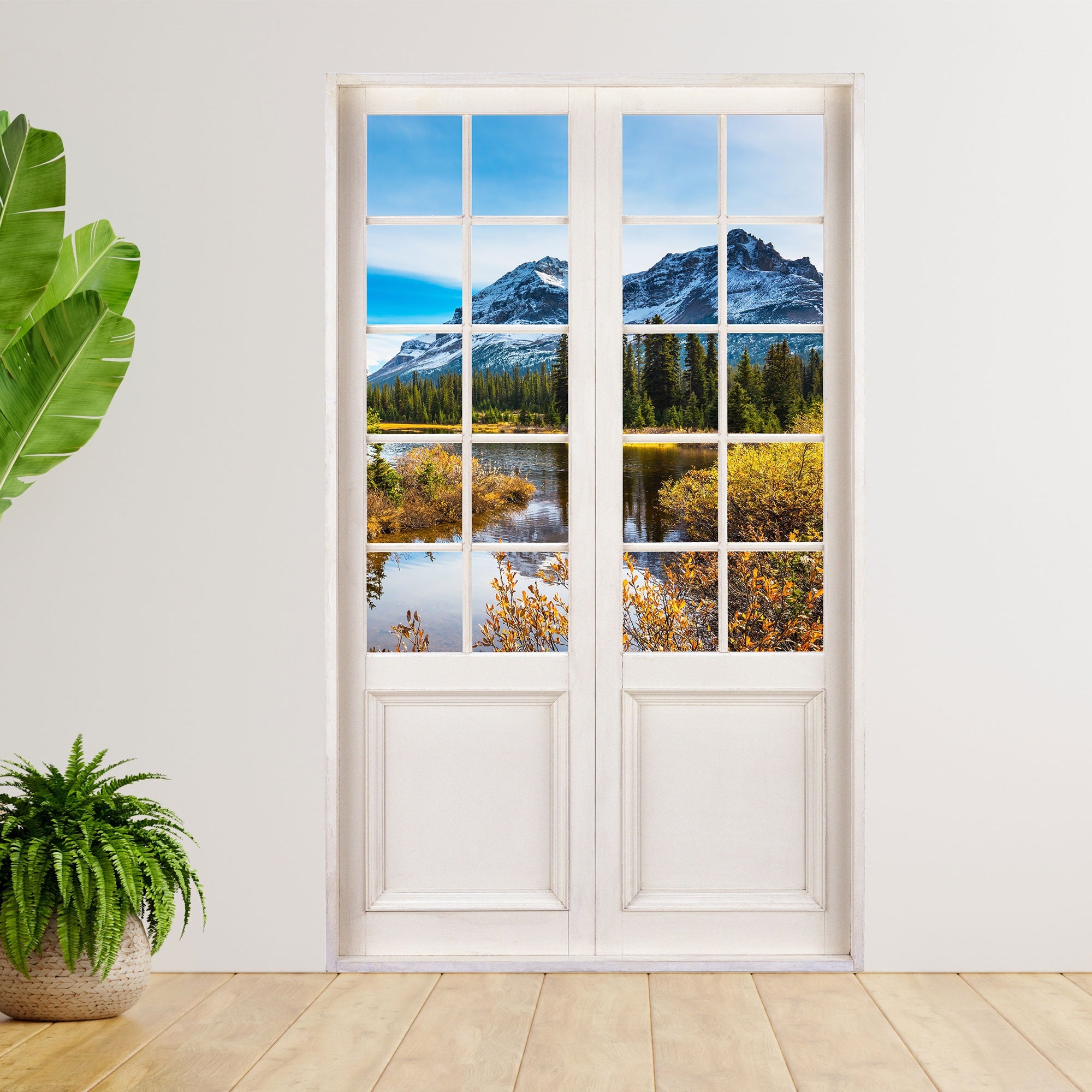Wandaufkleber einer Glastür mit Sprossenfenster und Blick auf Berg und Fluss für Schlaf- und Gästezimmer. Als Größenbeispiel an einer Wand neben großen Zimmerpflanzen verklebt.