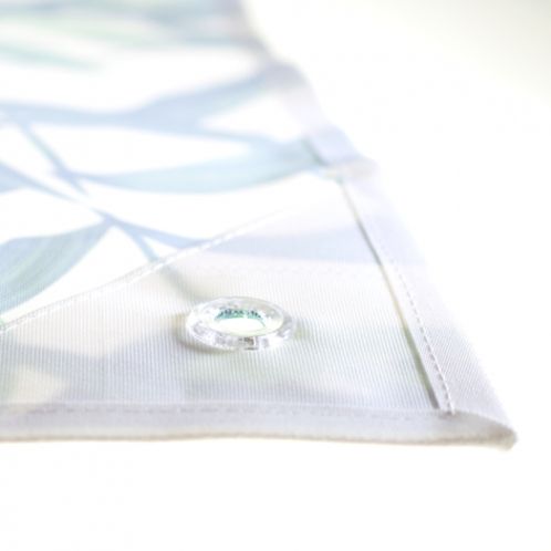 Dieses Bild zeigt einen weiteren detaillierten Ausschnitt eines Textils oder eines Drucks. Es ist erkennbar, dass der Stoff mit einem Ösenverschluss versehen ist, was darauf hinweist, dass es sich möglicherweise um ein Banner, ein Plakat oder eine Art von Wandbehang handelt. Der Rand des Stoffes ist sauber genäht, und die Öse ermöglicht das Aufhängen oder Befestigen des Materials an einer Wand oder einer anderen Struktur. Die Farbtöne und das Muster, das weiter im Bild sichtbar ist, scheinen weiterhin Blätt