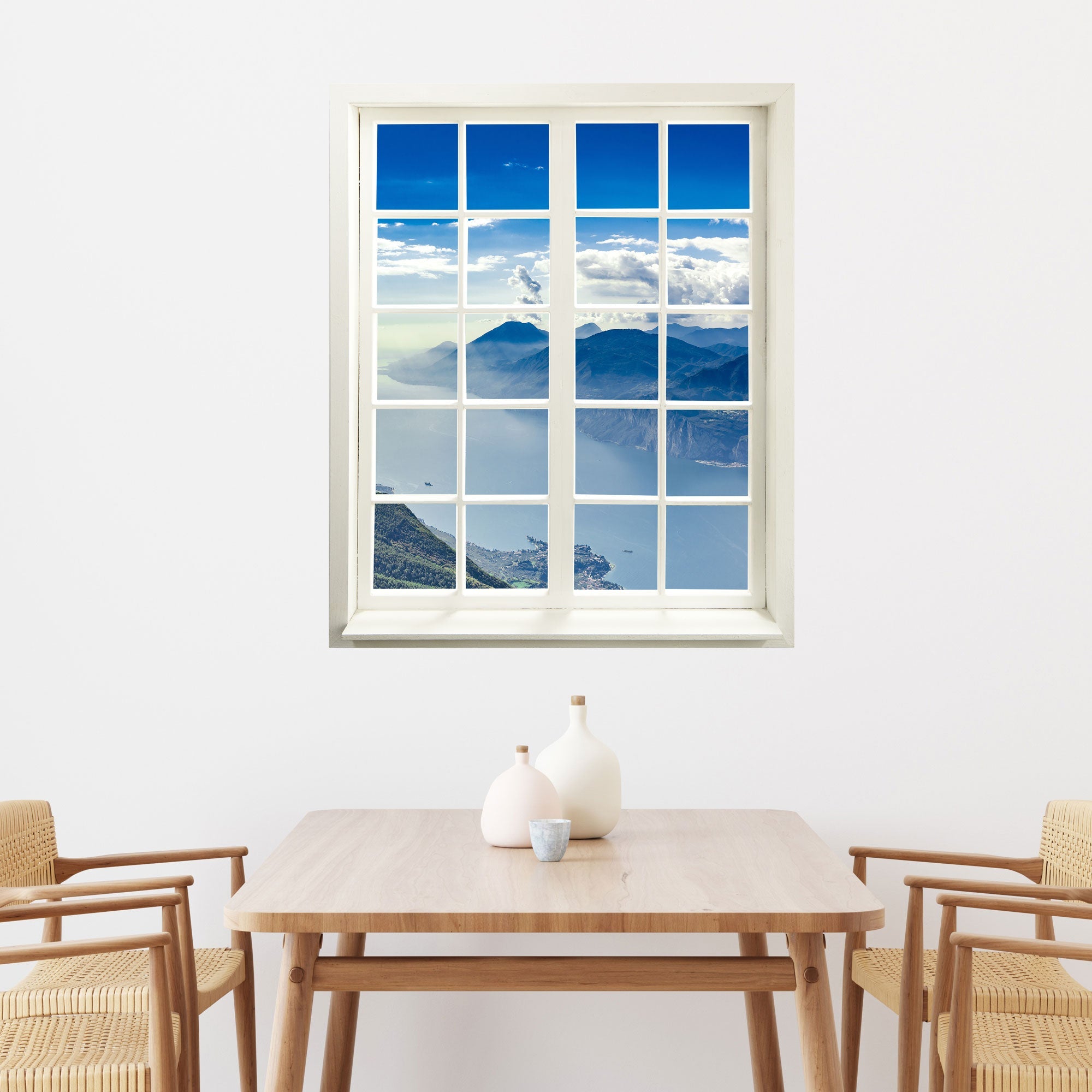 Gedrucktes Foto für Wände und Möbel, mit einem Sprossenfenstermotiv und weitem Blick auf ein Bergpanorama. Der Aufkleber mit geschlossenem Fensterrahmen ist über einem Esstisch an der Wand verklebt.
