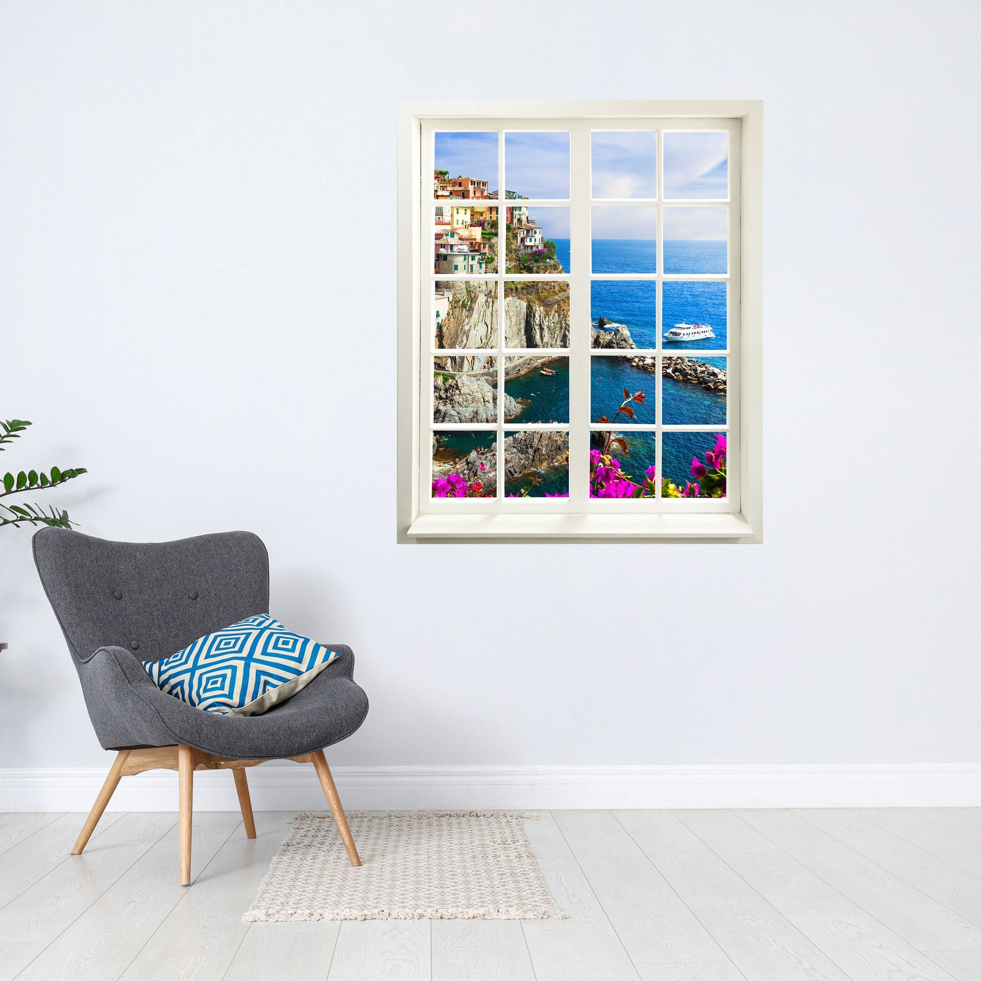 Selbstklebendes Wandaufkleber-Bild für Flur und Wohnzimmer oder Schlafzimmer. Hier ein Fensteraufkleber mit dem Motiv Cinque Terra an einer weissen Wand über einem grauen Sessel.