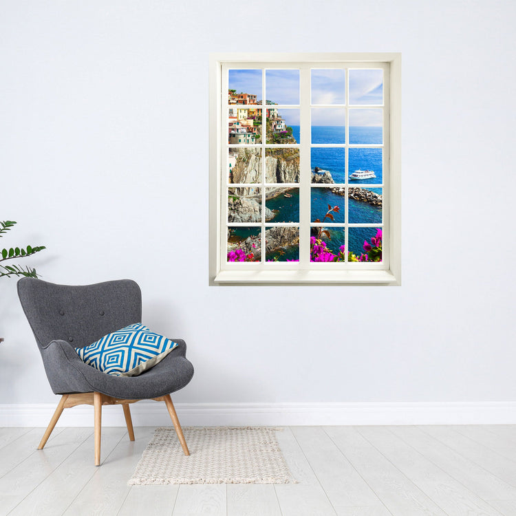 Selbstklebendes Wandaufkleber-Bild für Flur und Wohnzimmer oder Schlafzimmer. Hier ein Fensteraufkleber mit dem Motiv Cinque Terra an einer weissen Wand über einem grauen Sessel.