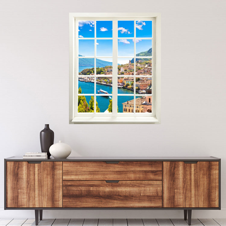 Selbstklebende Wandaufkleber-Bild Dorf am See für Flur, Bad oder Wohnzimmer. Das Motiv vom Fensterblick mit weissen Sprossen und dem "Dorf am See" ist an der Wand über einer Kommode verklebt.