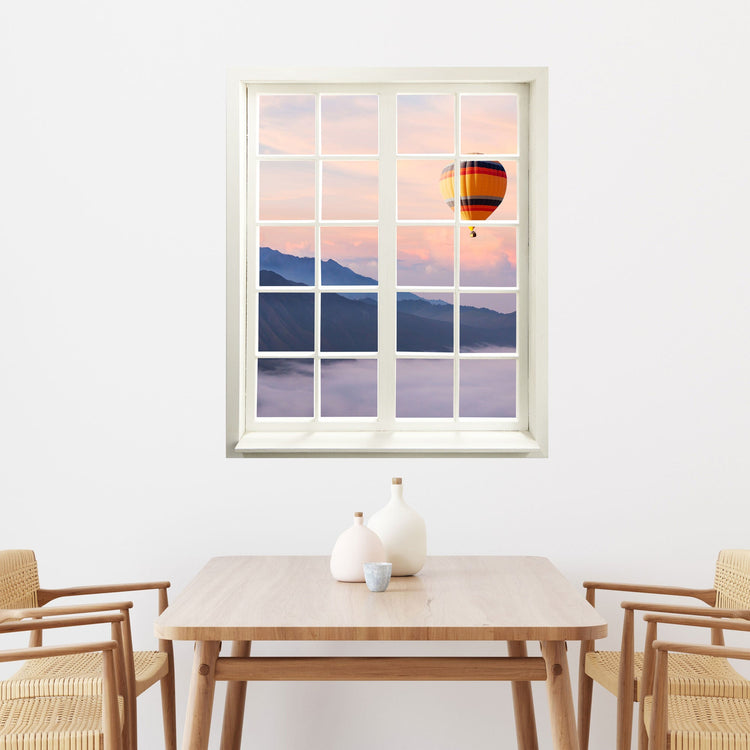 Wandtattoo bedruckt mit Fensterrahmen und tollem Naturbild mit Heißluftballon in Richtung Berge. Über einem Holz-Esstisch an einer Wand.