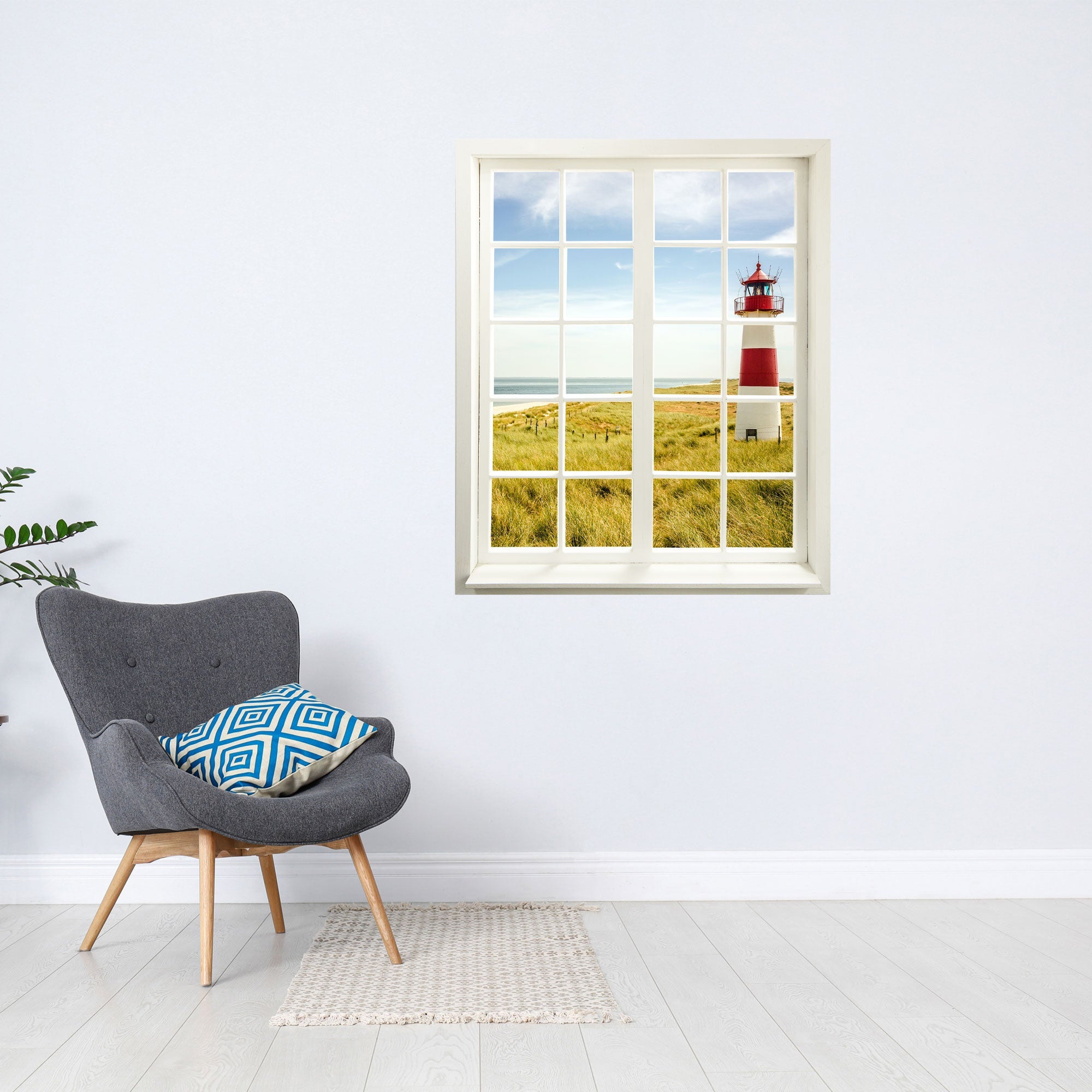 Wandtattoo Fensterblick "Leuchtturm" über grauem Sessel in hellem Zimmer.
