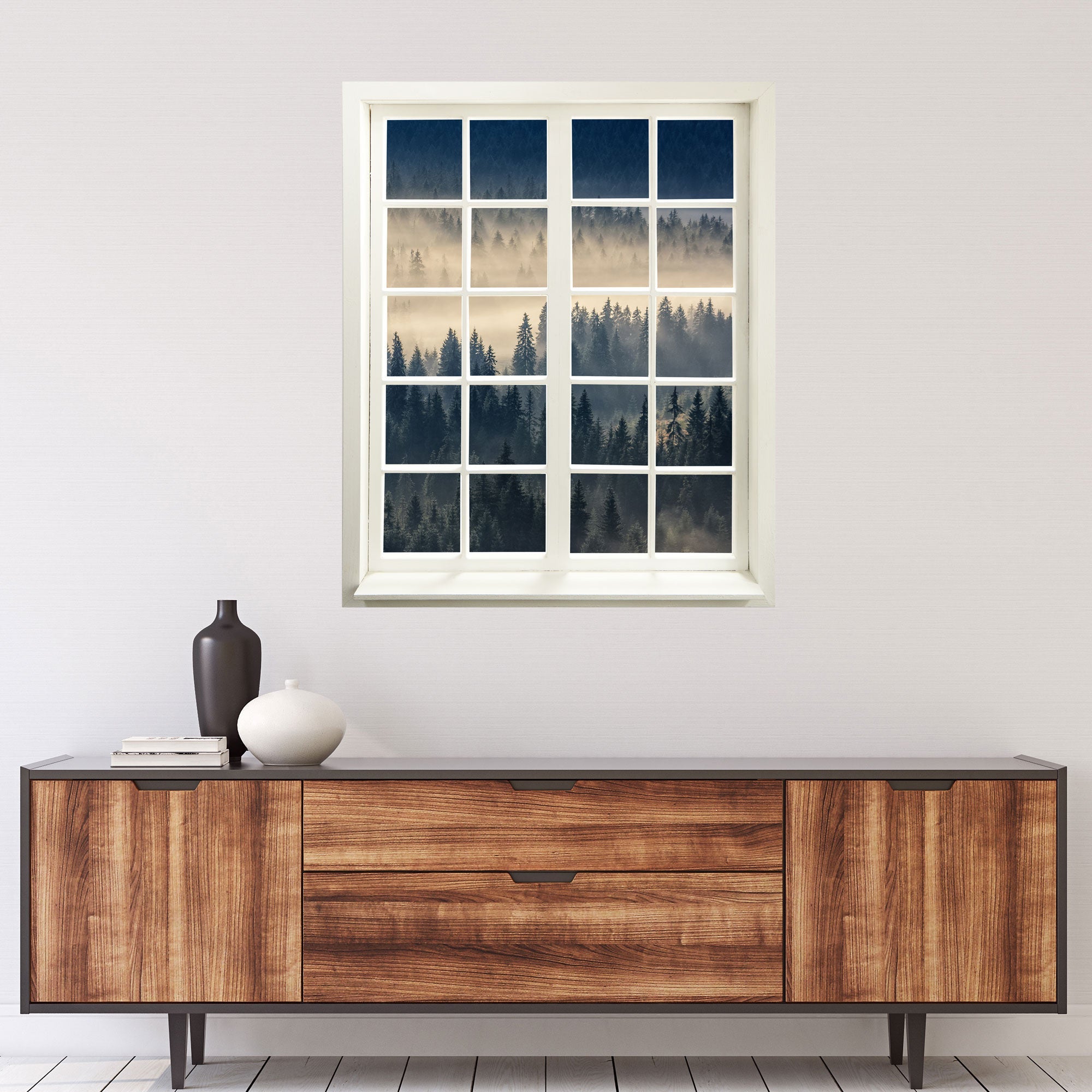 Wandtattoo Fensterblick "Nebelwald" über einer Kommode in Holzoptik, an einer weissen Wand.