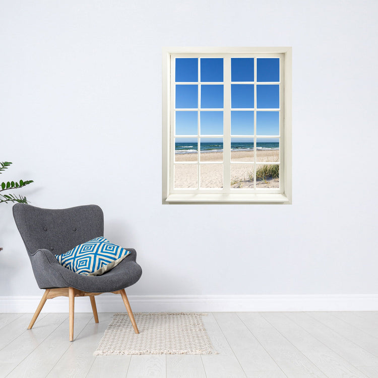Wandaufkleber Sprossenfenster mit toller Aussicht vergrößert Zimmer optisch. Hier das Motiv Ostsee und Meer an einer weissen Wand über einem grauen Sessel.