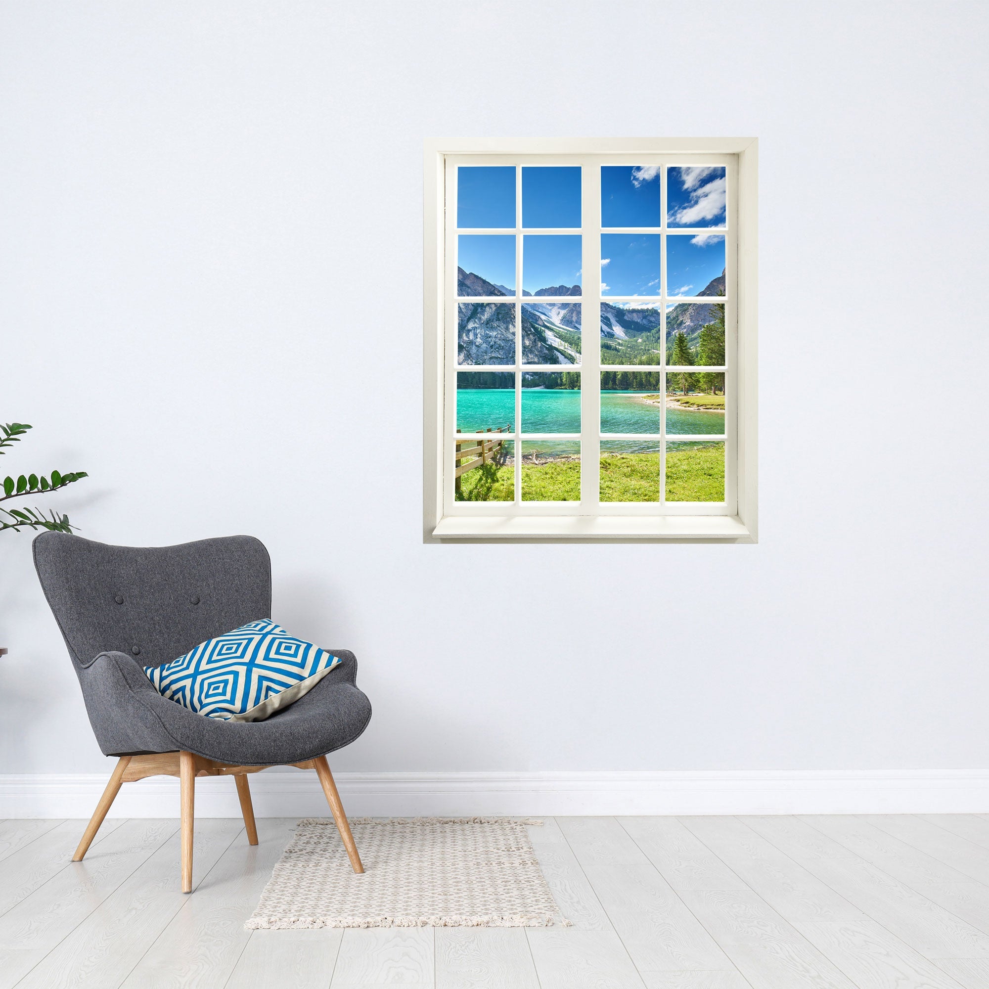 Wandtattoo Fenster mit Aussicht in die Natur "See-Türkis", verklebt an einer freien Wand über einem grauen Sessel.