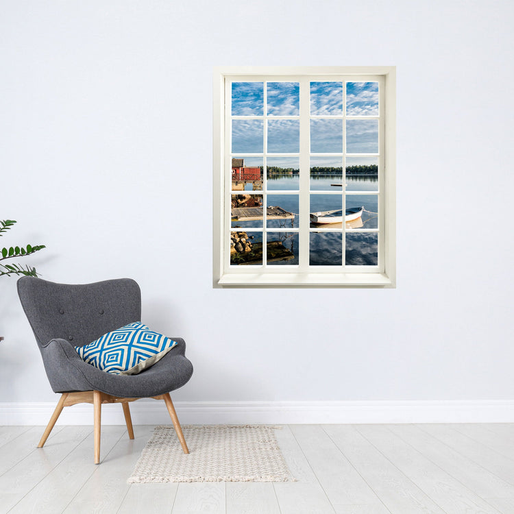 Wandaufkleber Sprossenfenster geschlossen, mit toller Aussicht auf ein Seeufer mit Steg und Boot, vergrößert Zimmer optisch für Flure und Gästezimmer. Als Beispiel hier an der Wand über einem grauen Sessel.