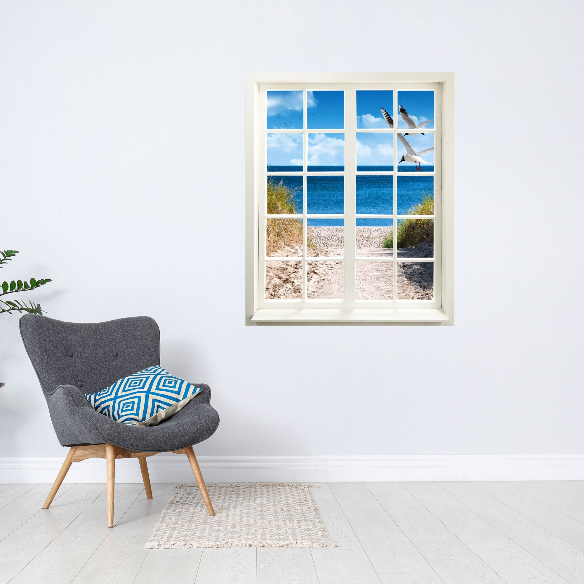 Wandtattoo Motiv Fensterblick "Strand mit Möwen" neben grauem Lesesessel.