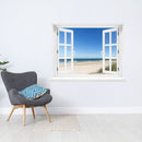 Offenes Fenster mit Blick auf Sandstrand, Meer und blauen Himmel – dekorativer Wandaufkleber mit 3D-Effekt für sommerliches Urlaubsfeeling im eigenen Zuhause. Als Dekoidee an einer weissen Wand neben einem grauen Sessel verklebt.