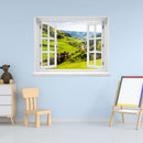 Offenes Fenster mit Ausblick auf grüne Hügel, ein idyllisches Dorf und bewaldete Berge – dekoratives Fensterbild mit realistischer 3D-Optik für naturnahes Wohnambiente. Als Dekoidee an eine blaue Wand im Kinderzimmer verklebt.