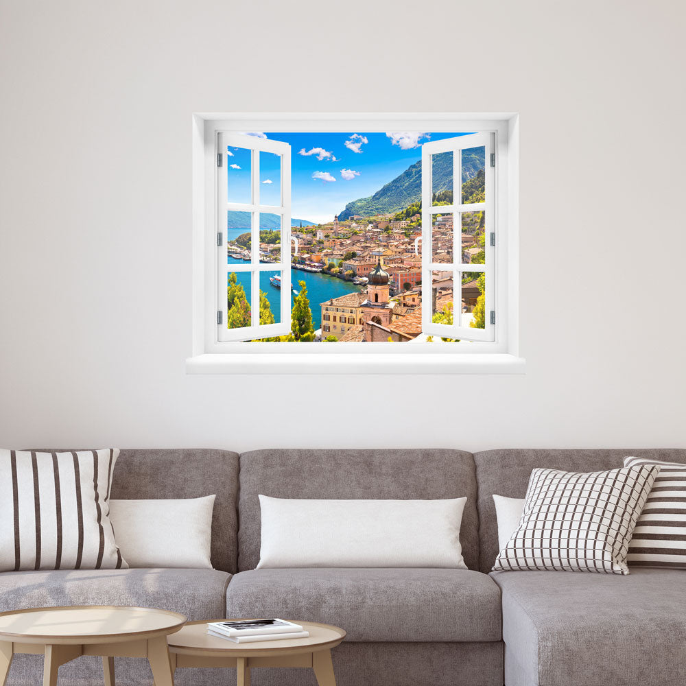 Wandsticker offenes Fenster "Dorf am See" Deko über einem grauem Sofa im Wohnzimmer.