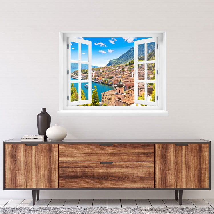 Wandsticker offenes Fenster "Dorf am See" über einem Sideboard aus Holz an einer weissen Wand.