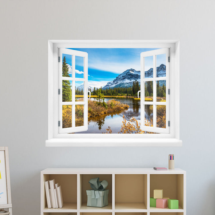 Wandaufkleber-Ansicht: offenes Fenster mit Blick auf eine idyllische Berglandschaft mit schneebedeckten Gipfeln, Nadelbäumen und einem ruhigen See im Vordergrund – Naturpanorama im Herbst. Als Dekoidee verklebt an einer weissen Wand im Kinderzimmer über einem Regal.