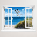 Wandaufkleber Aussicht aus dem geöffnetem Fenster auf Strand mit Möwen.