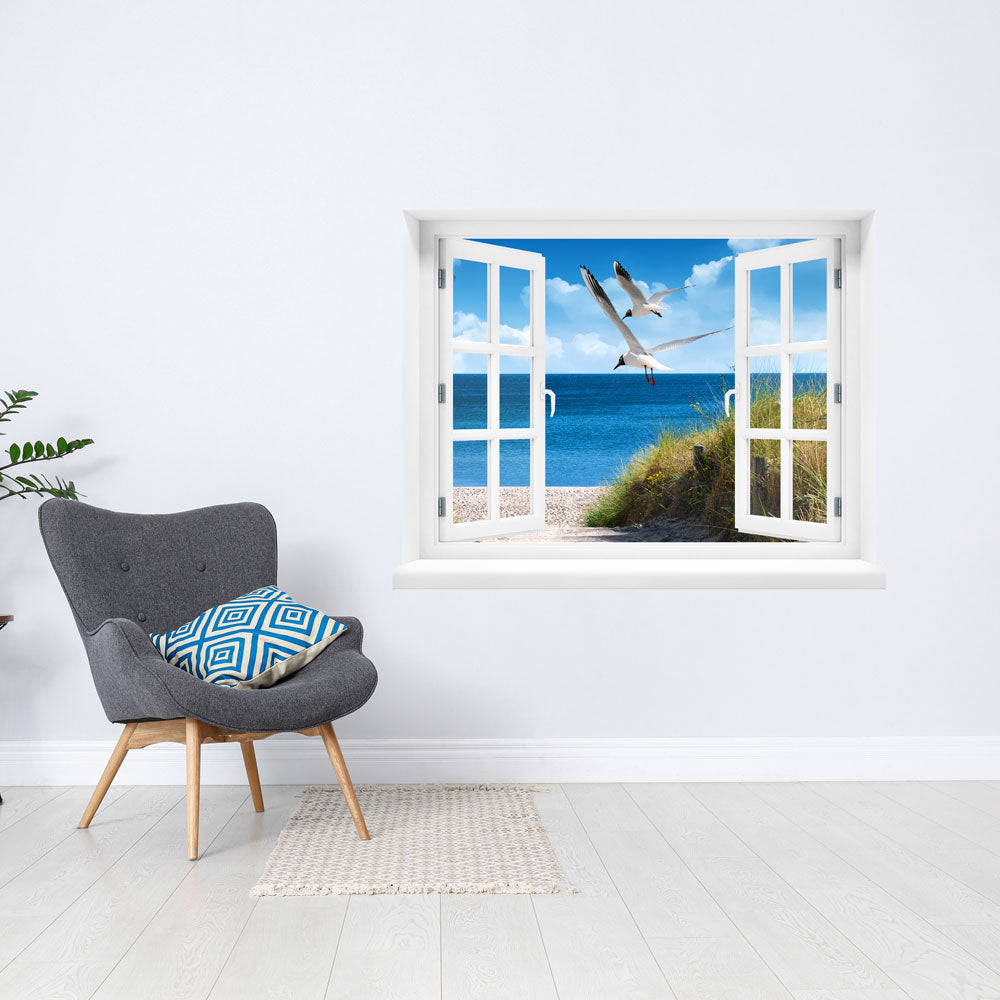 Selbstklebendes Wandbild mit schöner Aussicht auf Strand und Meer mit zwei Möwen, neben einem grauen Sessel.