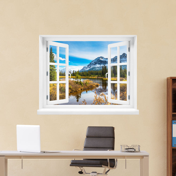 Wandaufkleber-Ansicht: offenes Fenster mit Blick auf eine idyllische Berglandschaft mit schneebedeckten Gipfeln, Nadelbäumen und einem ruhigen See im Vordergrund – Naturpanorama im Herbst. Als Dekoidee verklebt an einer beigen Wand im Büro über den Schreibtisch.