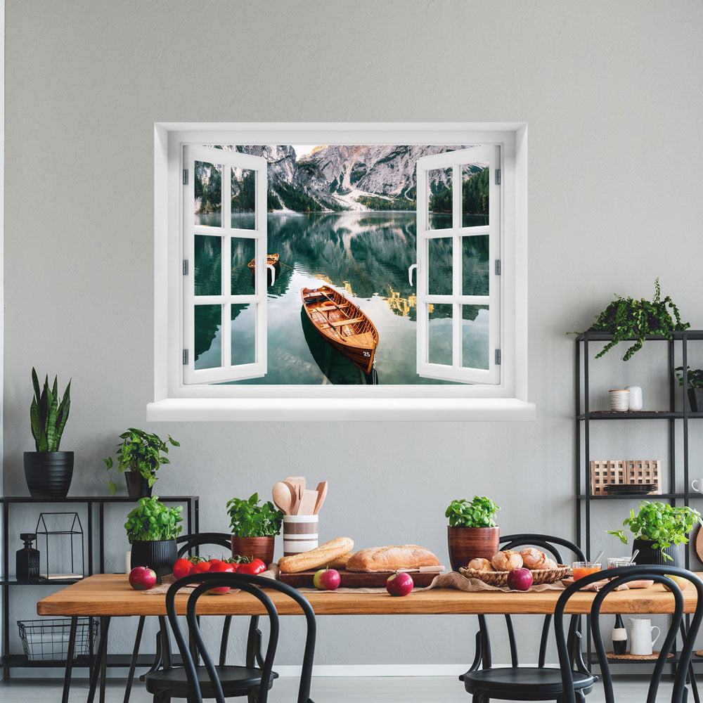 Wandaufkleber-Ansicht-offenes Fenster mit Blick auf ruhigen Bergsee mit Holzruderbooten, umgeben von steilen Felswänden und Wäldern – stimmungsvolle Naturkulisse in den Alpen. Als Dekoidee in einer Küche an einer weissen Wand über einem gedeckten Tisch erklebt.